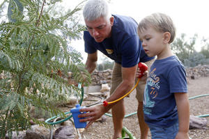 Tucsonan Scott Mencke, and his 3-year-old son, Reef, use water from their water harvesting cistern to water their garden