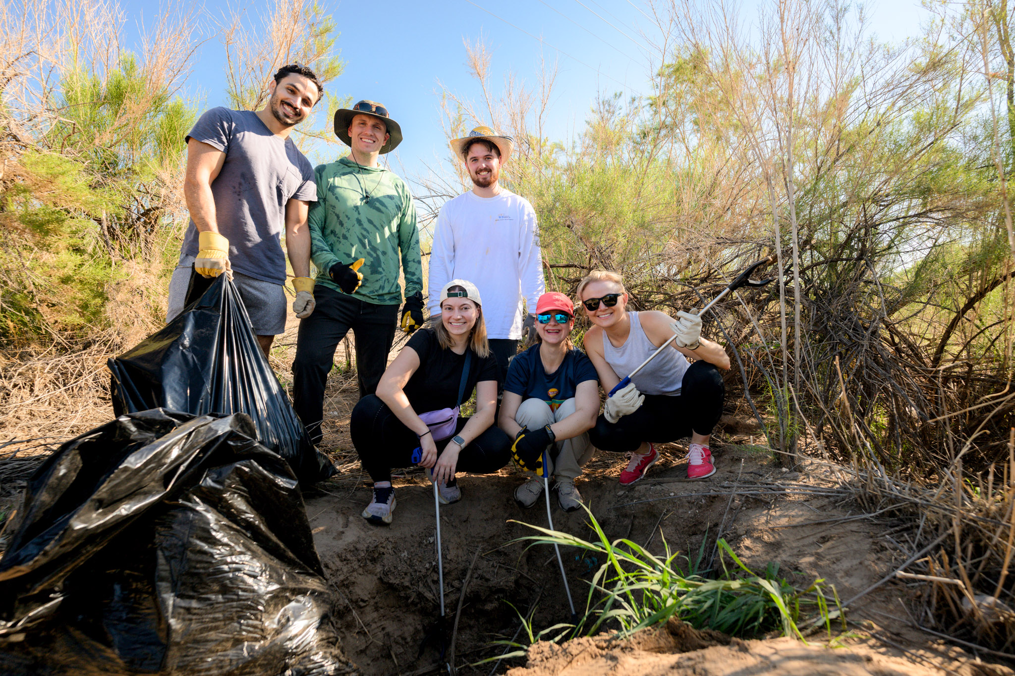 group of volunteers smiling after pulling out invasive plants