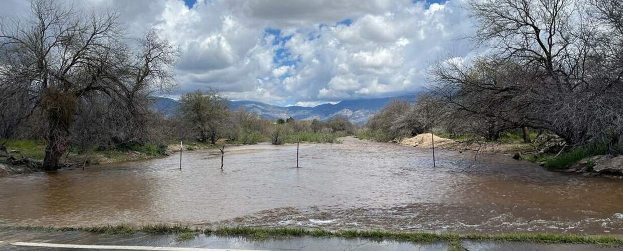 wide muddy water flows rapidly away having crossed the road in the foreground