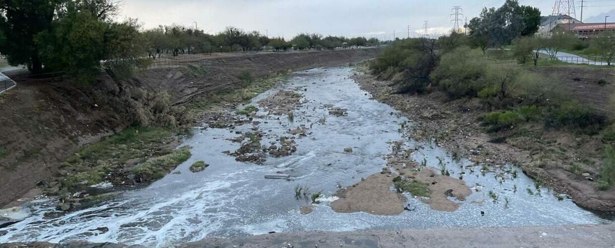 water flows rapidly away having crossed a low dam in the foreground