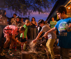 a group of kids building a beaver dame analog with sticks, mud, and leaves
