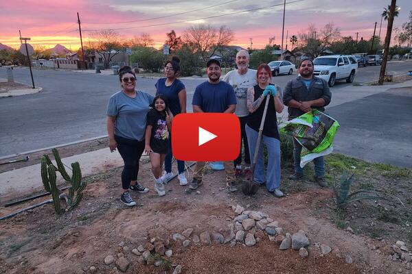 a group of people smiling at the camera in front of a newly created rain garden