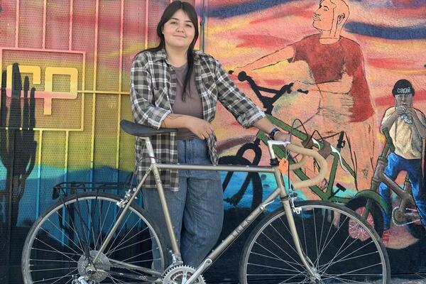 a woman with a bicycle in front of a mural