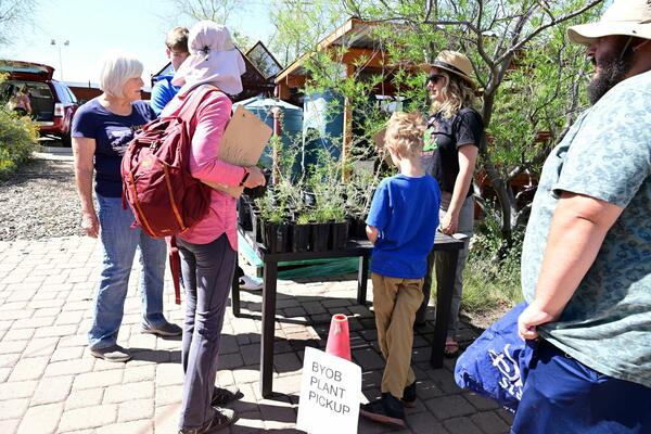 people of all ages standing around a table with native Sonoran desert plants