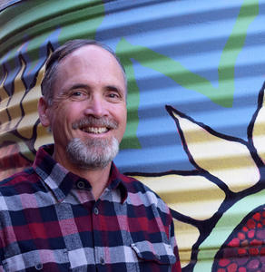 Richard Roati with his cistern. Photo by Owen Zerambo.