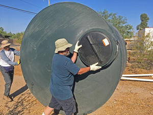 Steward In Place - Volunteers rolling large water harvesting cistern